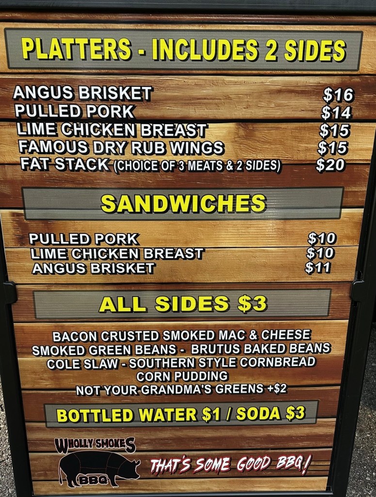 Menu board for Wholly Smokes BBQ food truck featuring items like Angus Brisket, Pulled Pork, Lime Chicken Breast, and various sides.